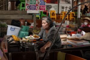 Vendedora cocinando platos tailandeses en un mercado callejero de Bangkok